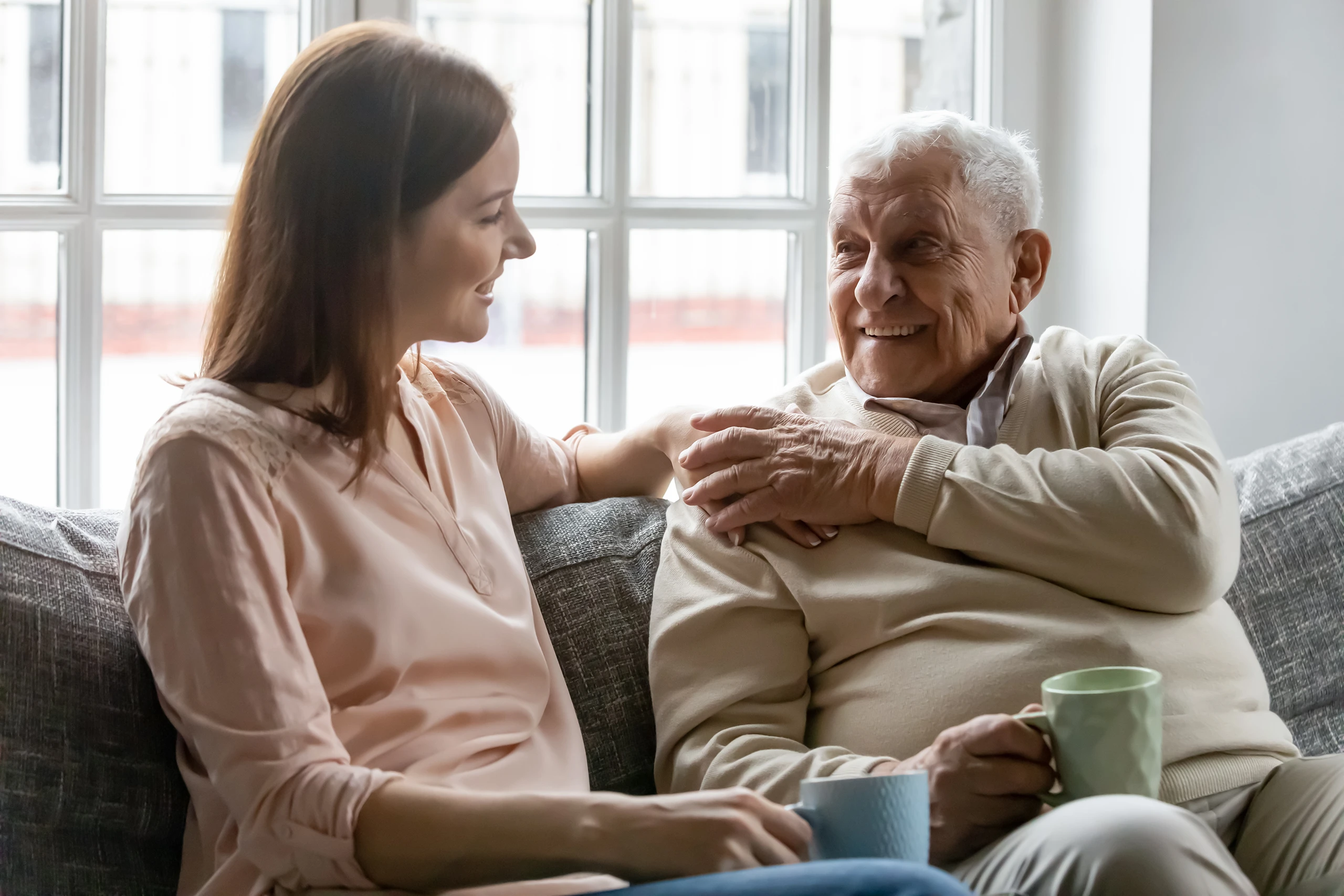 Junge Frau und älterer Mann trinken Kaffee und unterhalten sich